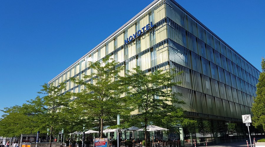 The exterior of Novotel Munich Messe, the published venue for DTD 2026. Photo via the organiser's official venue page.
